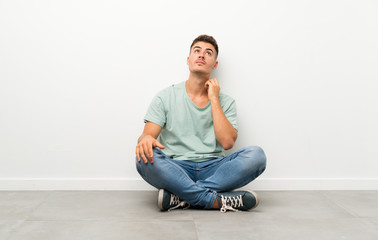 Young handsome man sitting on the floor thinking an idea