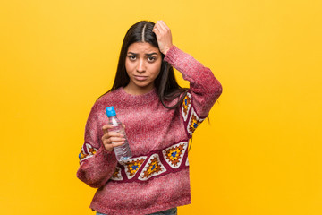 Young arab woman holding a water bottle being shocked, she has remembered important meeting.