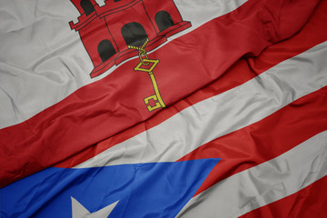 waving colorful flag of puerto rico and national flag of gibraltar.