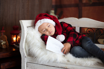 Obraz premium Sweet blonde toddler boy, sleeping with letter to Santa in hand, wishing present for the holidays