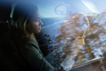 Businesswoman text messaging while a driving car.
