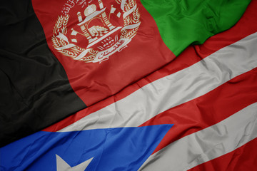 waving colorful flag of puerto rico and national flag of afghanistan.