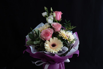 Beautiful bouquet with pink roses and gerberas on a black background.