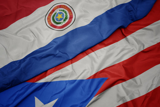 waving colorful flag of puerto rico and national flag of paraguay.