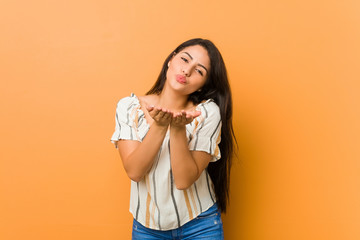 Young curvy woman folding lips and holding palms to send air kiss.