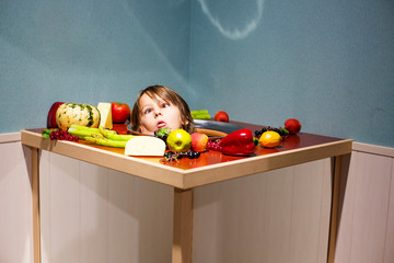 Kid, playing in a funny panel with plate and vegetables and his head on the plate