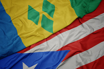 waving colorful flag of puerto rico and national flag of saint vincent and the grenadines.