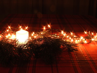 A candle and Christmas light on a table