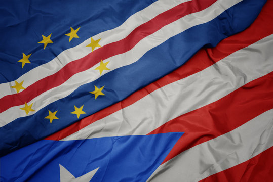 waving colorful flag of puerto rico and national flag of cape verde.