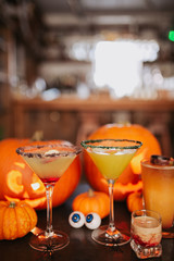 A close up shot of Halloween cocktails with carved pumpkins in the background. Concept of seasonal traditions and celebration in hospitality. Selective focus on the cocktails.