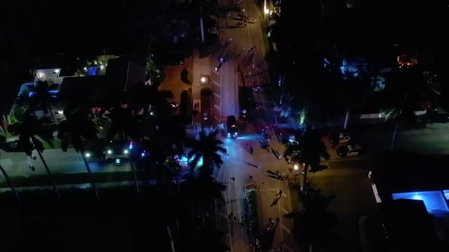Aerial orbit shot people trick or treating in a residential neighborhood with police lights