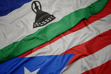 waving colorful flag of puerto rico and national flag of lesotho.