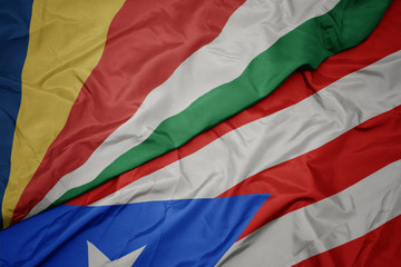 waving colorful flag of puerto rico and national flag of seychelles.