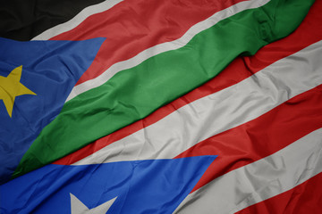 waving colorful flag of puerto rico and national flag of south sudan.