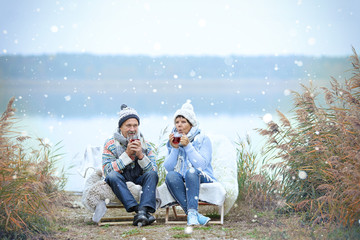freudiges Paar trinkt heißen Punsch am See im Winter