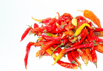 dried hot chili peppers, yellow and green pods on a light background