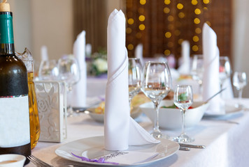 napkin on a plate on a set table, glasses, bottle of wine, Banquet table