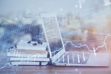 Stock market graph on background with desk and personal computer. Double exposure. Concept of financial analysis.