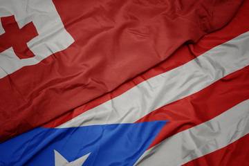 waving colorful flag of puerto rico and national flag of Tonga .