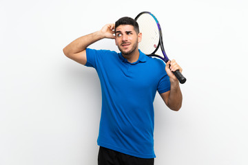 Handsome young tennis player man over isolated white wall having doubts and with confuse face...