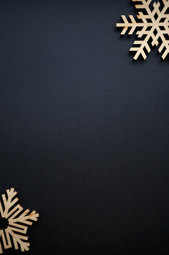 Happy New Year and Christmas background.Hand made wooden snowflakes on black backdrop with empty space for text.Handmade snow flake crafts made from rustic wood for winter holiday decor