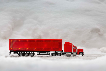 Festive truck in red. toy car rides on the background of real snowdrifts. Winter. Christmas holidays.