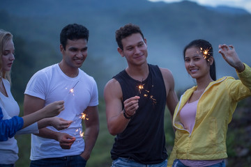 Group of friends camping together with sparklers and enjoy picnic party in a countryside.Travel vacation and Adventure activity time concept