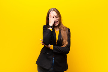 young pretty businesswoman laughing and slapping forehead like saying d‚Äôoh! I forgot or that...