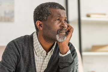 depressed, senior african american man holding hand near face and looking away
