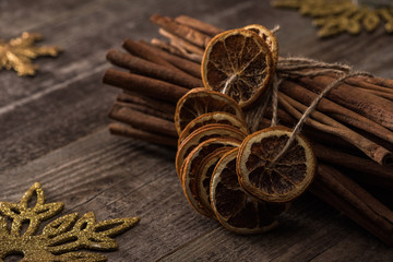 dried citrus slices on thread near cinnamon and snowflakes on wooden background