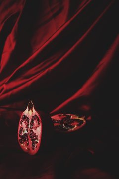 Split pomegranate on red fabric backdrop