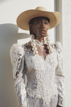 Model in white formal dress with oversized pearl earrings