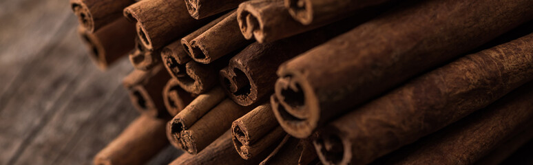 close up view of cinnamon sticks on wooden rustic table, panoramic shot