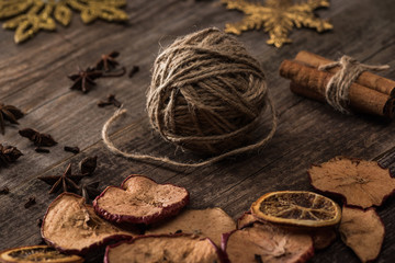 dried citrus and apple slices near ball of thread on wooden surface