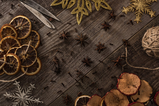 top view of dried citrus and apple slices near snowflakes, scissors, thread and anise on wooden surface