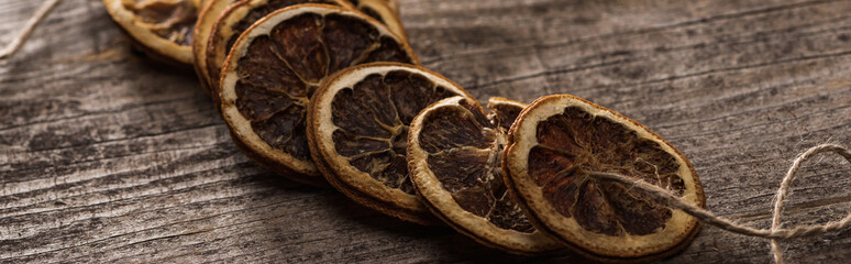 dried orange slices on rope on wooden surface, panoramic shot