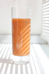 Glass of orange smoothie on a white table