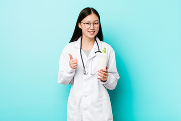 Young asian dermatologist girl smiling and raising thumb up