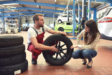 Beratungsgespräch mit Kundin in der Autowerkstatt zum Reifenwechsel // Consultation with customer...
