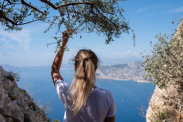 A girl stands on a mountain and looks at a beautiful harbor