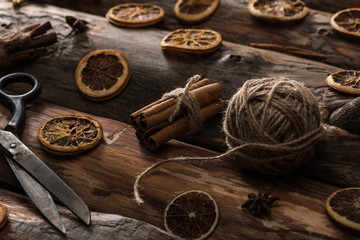 anise, cinnamon sticks, scissors, ball of thread on wooden background
