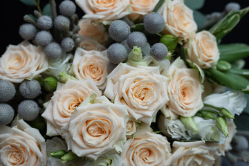 Beautiful wedding bouquet of bushy cream rose, eucalyptus, Brunei, Pittosporum and Lisianthus on a black background.
