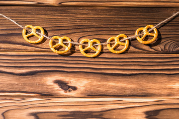 Garland of pretzels Salted Cookies hanging on a rope.  Rustic Christmas decoration.  Wooden boards background