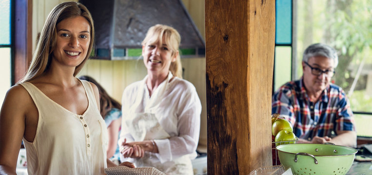 Portrait of smiling woman standing with her parents in kitchen