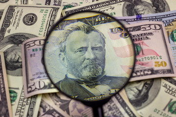 Fifty usa dollar bill inspected under a magnifying glass. Financial concept, money background.