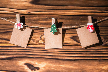 garland with cute empty little kraft paper stickers hanging on a rope on wooden clothespins. Rustic Christmas decoration. Copy space. Wooden boards background