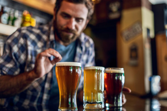 Man looking at beer glass while standing in the bar