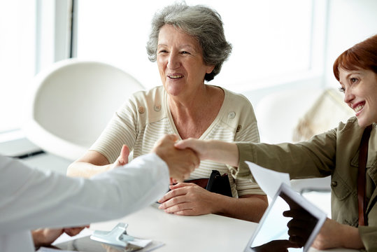 Smiling mother and daughter shaking hands with doctor in clinic