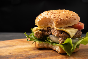 Fresh homemade hamburgers, delicious fresh vegetables, lettuce, tomatoes, cheese that are bitten on a cutting board, free space for messages