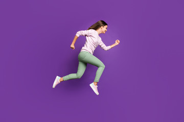 Fototapeta na wymiar Full length body size photo of excited cheerful girl wearing green trousers aspiring to come on time for sales running towards shopping center jumping up isolated over purple vivid color background